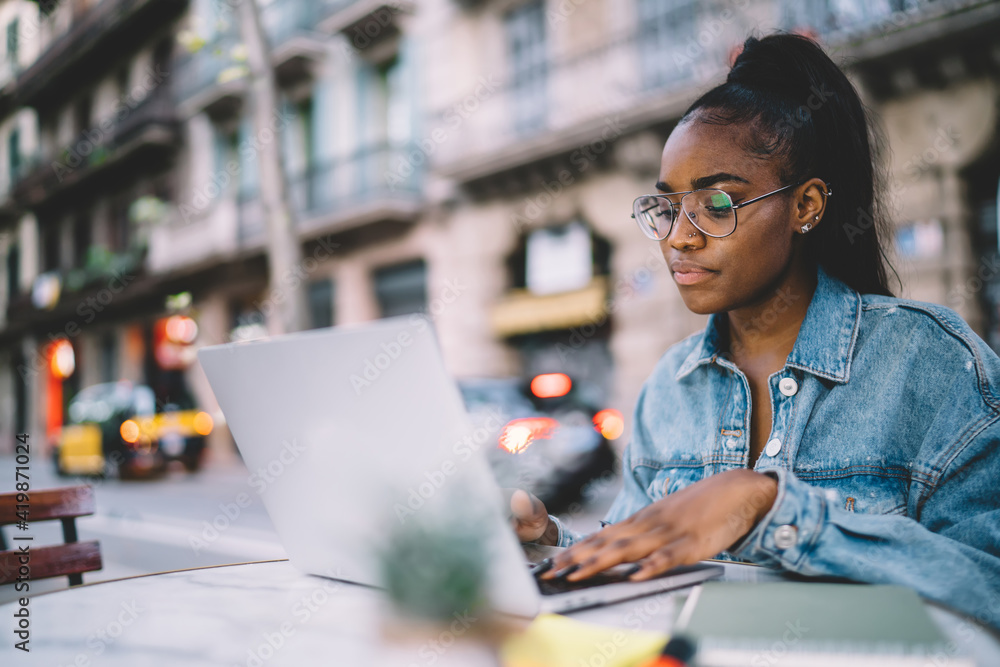 Aufkleber dark skinned woman in glasses typing on laptop computer share content in blog browsing web pages and