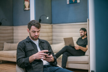 Fototapeta premium Men work with a smartphone and laptop in the office