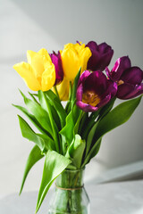 Lilac purple tulip flowers on table. Spring bouquet flowers in vintage vase. Floral concept. Floral background.  White decoration and light background