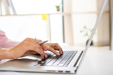 Asian female finance or accountant is using laptop to report company investment results, reporting concept. And examine the investment results