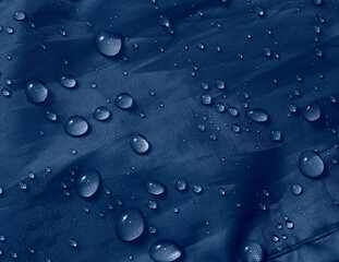 Water drops on waterproof membrane fabric. Detail view of texture of blue waterproof cloth.