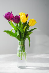 Lilac purple tulip flowers on table. Spring bouquet flowers in vintage vase. Floral concept. Floral background.  White decoration and light background