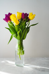 Lilac purple tulip flowers on table. Spring bouquet flowers in vintage vase. Floral concept. Floral background.  White decoration and light background