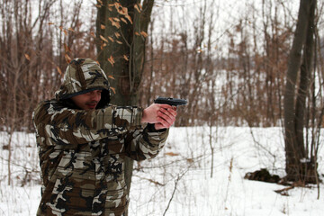 Soldier shooting with a pistol in the forest in winter