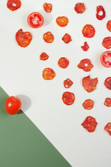 Fototapeta premium Red tomatoes chips and dehydration slices on white background with green corner. Two-color background 
