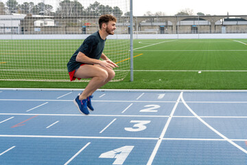 Obraz premium Hard working young runner boy doing warm-up in blue running track.