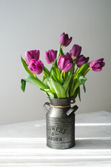 Lilac purple tulip flowers on table. Spring bouquet flowers in vintage vase. Floral concept. Floral background.  White decoration and light background