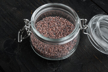 Indian Black salt, Kala namak hindi Healthy food concept, in glass jar, on black wooden background
