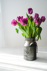 Lilac purple tulip flowers on table. Spring bouquet flowers in vintage vase. Floral concept. Floral background.  White decoration and light background