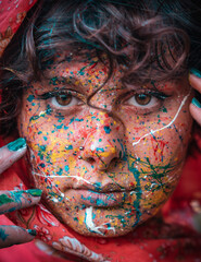 Close-up Portrait of a brunette young woman with Multi Colored Face Paint. Holi festival of colors,...