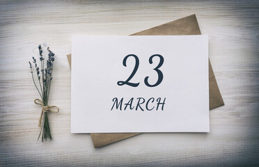 march 23. 23th day of the month, calendar date. White blank of paper with a brown envelope, dry bouquet of lavender flowers on a wooden background. Spring month, day of the year concept