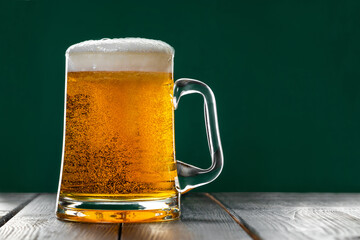 Mug of light beer with foam on a green background. Traditional Irish drink. Celebrating St. Patrick's Day.