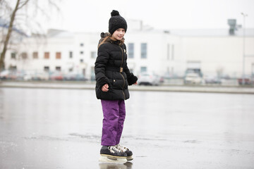 The girl goes ice-skating in the winter against the background of the city.