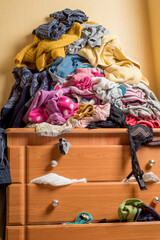 open chest drawers with drop-down clothes and piles of clothes around in a mess.Close-up