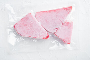 Frozen Tuna fish steak in a vacuum  plastic package, on white stone  background, top view flat lay