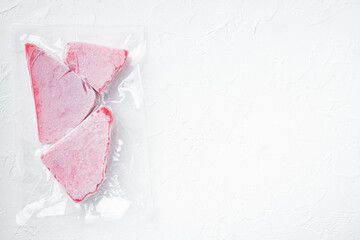 Frozen tuna steak vacuum pack, on white stone  background, top view flat lay , with copyspace  and space for text