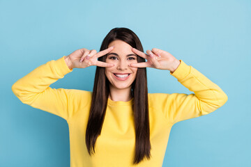 Photo of funny lovely lady two v-signs cover eyes look camera wear yellow jumper isolated blue background