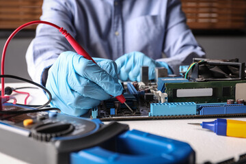Technician repairing electronic circuit board at table, closeup