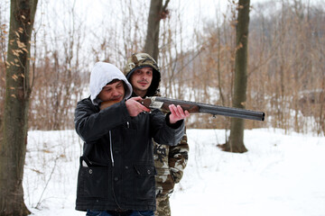Twin brothers with a shotgun in the winter forest