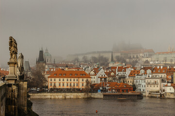 Postcard view of Prague Castle in mist from Charles Bridge,Czech republic.Famous tourist destination.Prague panorama.Foggy morning in city.Amazing European cityscape.Inversion weather outdoors.