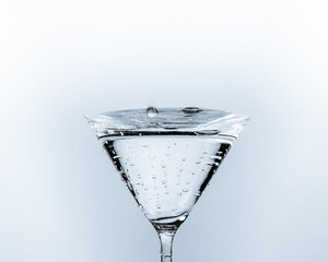 Close-up of water drop falling into a glass on white background