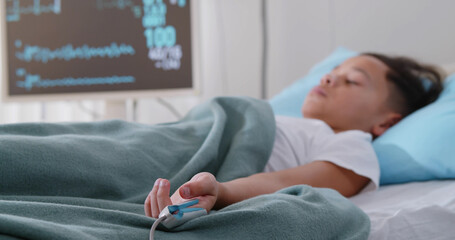 Little afro boy sleeping in hospital bed attached to monitors