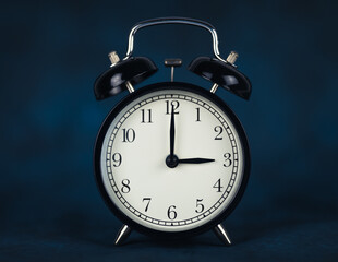 The time is three hours. The time is 3:00 or pm. Retro clock. Dark background. Copy space and cut...