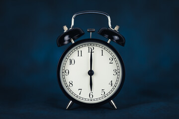 The time is six o'clock in the morning. Time - 06-00. Retro clock. Dark background. Copy space and...