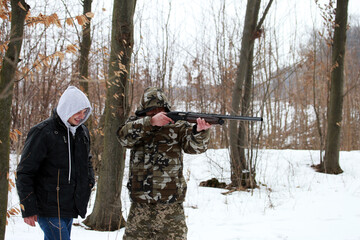 Twin brothers with a shotgun in the winter forest