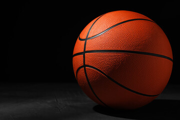 Obraz premium Basketball ball on grey stone table against dark background, space for text