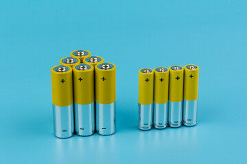 Photo of gray-yellow alkaline AA batteries on blue background. Recycling of rechargeable NiMH...