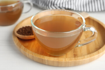 Glass cup of delicious buckwheat tea on white wooden table, closeup