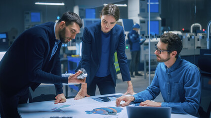 Fototapeta na wymiar Modern Factory Office Meeting Room: Diverse Team of Engineers, Managers Talking at Conference Table, Look at Blueprints, Inspect Mechanism, Use Laptop. High-Tech Facility with CNC Machines