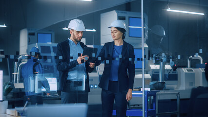 Modern Factory: Female Project Manager, Male Engineer Standing in High Tech Development Facility, Talking and Using Tablet Computer. Contemporary Facility with CNC Machinery, Robot Arm Production Line