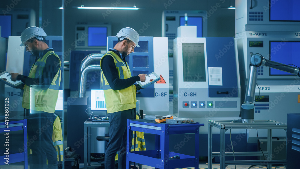 Poster Modern Factory: Professional Engineer Wearing Safety Vest and Hardhat, Uses Industrial Digital Tablet to Program and Manipulate Robot Arm, Optimizing Production Line. Workshop with CNC Machinery