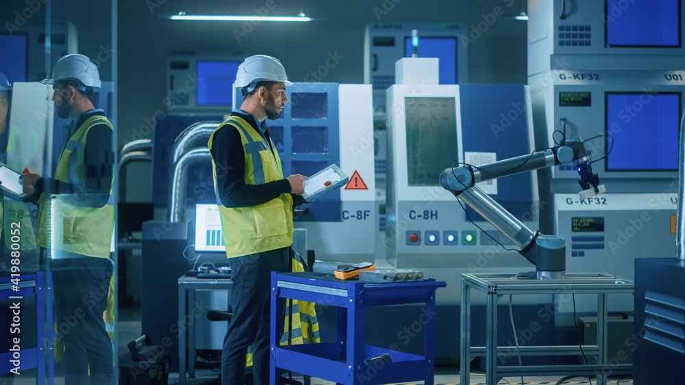 Fototapete modern factory: professional engineer wearing safety vest and hardhat, uses industrial digital table