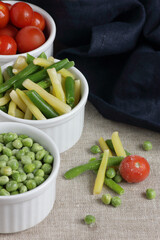 Frozen vegetables assorted in bowls isolated on white background, closeup, saving leftovers, food storage concept and eating meals at home concept