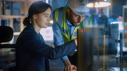 Modern Factory Office: Male Project Manager Talks to a Female Industrial Engineer who Works on Computer. Professional Teamwork, Specialists Solving Problems, Finding Solutions