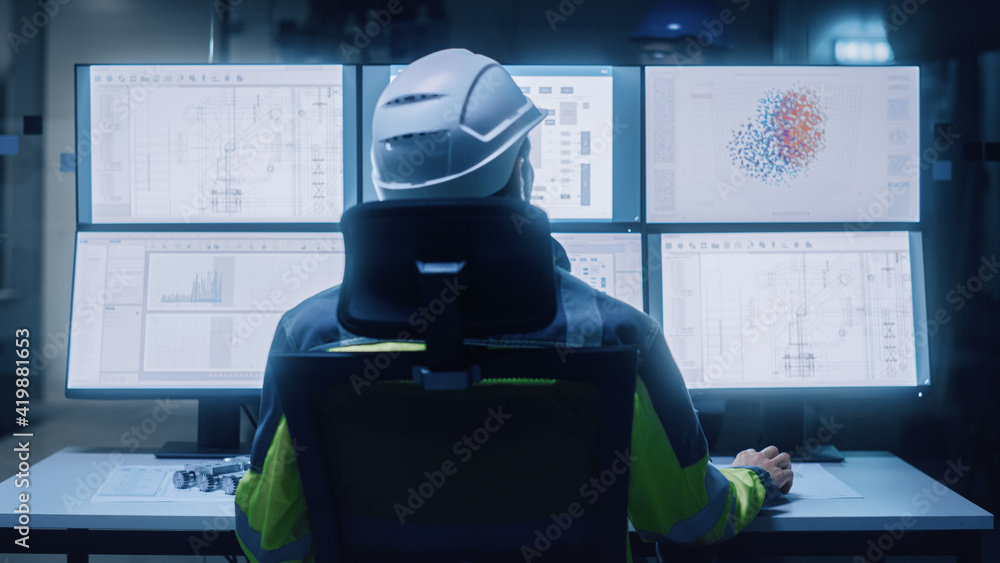 Poster Industry 4.0 Modern Factory: Facility Operator Wearing Hardhat and Safety Vest Controls Workshop Production Line, Uses Computer with Screens Showing Machinery Control Operation UI. Back View Shot