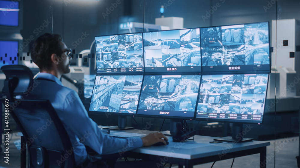 Poster Industry 4.0 Modern Factory: Security Operator Controls Proper Functioning of Workshop Production Line, Uses Computer with Screens Showing Surveillance Camera Feed. High-Tech Security