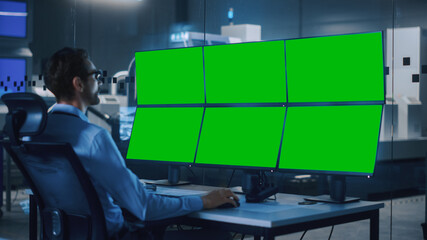 Industry 4.0 Modern Factory: Security Operator Controls Proper Functioning of Workshop Production Line, Uses Computer with 6 Screens Showing Green Screen Mock up Template.