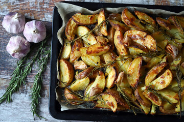 Appetizing baked potato wedges. Country-style potatoes on a baking sheet. Potatoes with herbs and garlic.