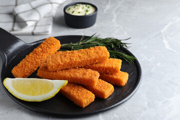 Fresh breaded fish fingers and lemon served on light grey table