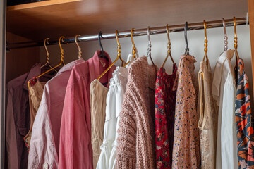 Pink wardrobe. Lots of delicate light summer clothes on hangers in the closet..Decluttering