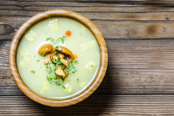 Creamy mushroom soup in a bowl on wooden background. Top view, space for text.