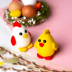 Easter chickens and hens made of wool on the background of Easter decor and a pink background. Wool decor for home decoration