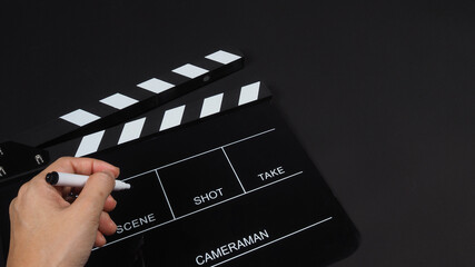Fototapeta na wymiar Hand is holding pen and Black Clapperboard or clap board or movie slate use in video production ,film, cinema industry on black background.