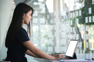 Portrait of young female designer is sitting at graphic studio in front of laptop computer while...