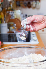 Person making bread in home kitchen adding ingredients to make the dough