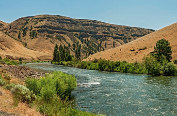 A sweeping view of the Yakima River Canyon showing an S curve of the river with greenery along the banks, some trees and the brown arid hillsides on a beautiful summer day_07072009_3..